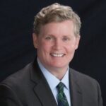 A man in suit and tie smiling for the camera.